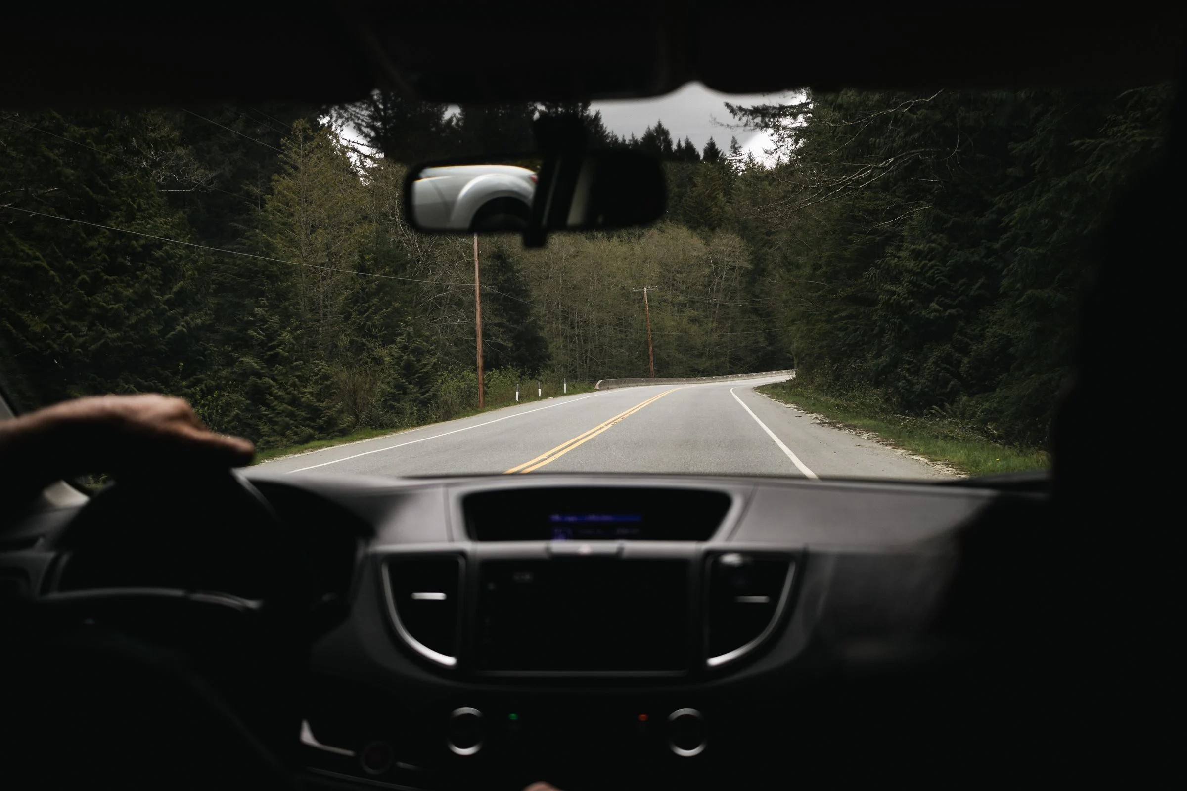 Blick aus einem Fahrzeug auf eine kurvige Waldstraße – Symbolbild